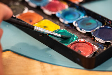 Colourful palette with many circle colours for brushes with a brush in a green colour