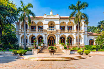 Obraz premium Colonial style India luxury estate home, arched windows, white facade, stone stairs, two story. Fictitious building