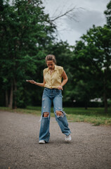 Fototapeta premium A young girl having fun alone in the park, dancing and enjoying herself on a peaceful afternoon
