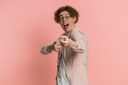 Happy mime Caucasian curly haired man in jacket pulling an imaginary unreal invisible rope, puts lot of effort into showing how enduring, strong he is. Young guy isolated on pink background indoors