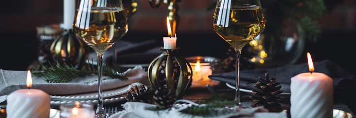 Rustic elegant table decor for Christmas family dinner. Center piece with white candle, pine cone, fir tree branches. Zero waste eco-friendly home decoration. Cozy atmosphere, wooden background banner