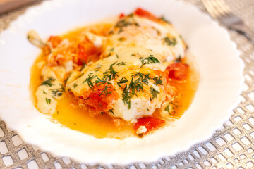 Israeli dish Shakshuka. Eggs with tomatoes on a white plate.