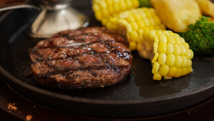 close up of beef steak and blackpaper sauce with corn, broccoli and boiled potatoes on a wooden table