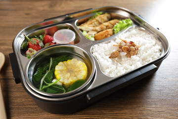 Lunch or bento is put in a lunch box. There are vegetables, side dishes, fruit and also rice.