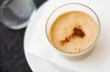 Obraz premium Baked sweet dessert coffee mousse made from fermented milk product, gently creamy color and lush texture. Dessert is decorated with scattering of cocoa powder