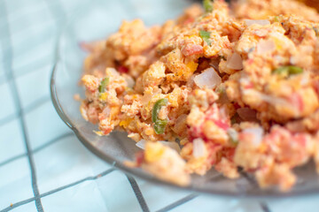 Plano a detalle de huevos revueltos con picante, cebolla y jitomate rojo 