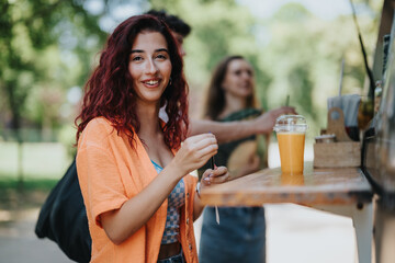 Friends having a fun time in the park, enjoying fresh drinks from a food truck. Smiling and engaging in casual conversation.