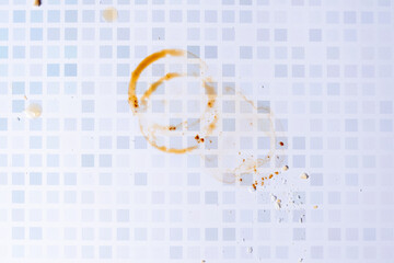 Circular stains from the rim of a coffee cup on a bluish checkered countertop.