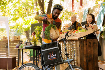 Deliveryman picking up fresh produce orders with a thermal backpack, working with a small business owner, and selling organic products. Farmers are selling healthy, fresh bio farm vegetables online.