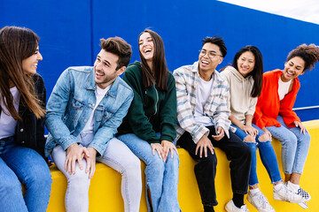 Obraz premium Young group of happy student friends having fun hanging out together sitting outside. Youth community concept