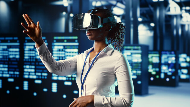 African american experienced specialist immersed in virtual reality at data center, doing units maintenance. Adept professional using VR headset to optimize servers performance, checking operations