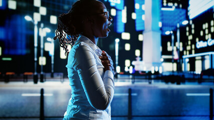 African american businesswoman dancing around in empty city streets at night, feeling happy after receiving promotion at work. Joyful woman enjoying herself while strolling in town center