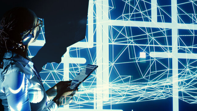 Manager overseeing dimly lit server room, running code on tablet, troubleshooting and upgrading technologically advanced hardware clusters made of servers, networking systems and storage arrays