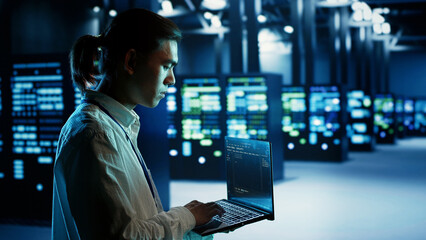 Fototapeta premium Certified asian technician running code on laptop, maintenancing and upgrading data center equipment designed to accommodate server rows, networking systems and storage arrays