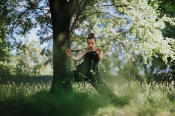 Lovely girl dancing in nature, showcasing a graceful modern dance performance amidst lush green surroundings.