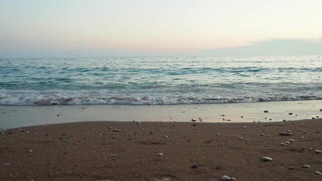 Waves gently lap at shore during stunning sunset over ocean. Golden sunlight reflects off waves as they roll onto shore, creating tranquil atmosphere at sunset by sea. Montenegro summer Canj
