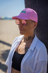 Cancer survivor wearing a pink cap on a sandy beach