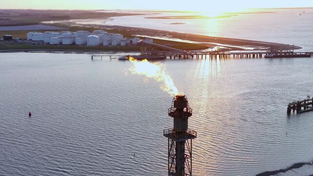 Aerial view of a chemical plant at sunset. Drone shot. Curling fire and cumin smoke filling the sky. Smoking chimneys from the factory. Chimneys of an oil refinery at sunrise pollute the environment