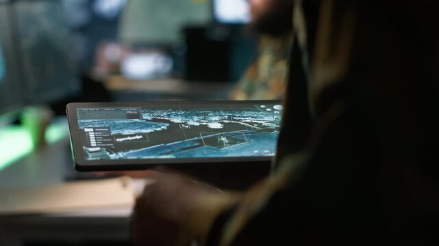 Army operative using tablet in command center housing operational missile defense system designed to intercept ballistic rockets. Close up of expert using tracking software on device, camera A