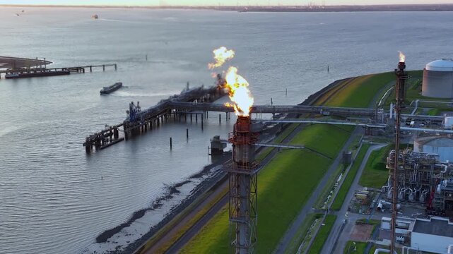 Aerial view of a chemical plant at sunset. Drone shot. Curling fire and cumin smoke filling the sky. Smoking chimneys from the factory. Chimneys of an oil refinery at sunrise pollute the environment
