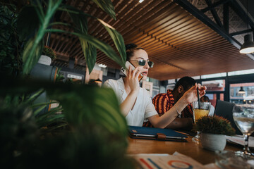 Diverse group of people collaborating in a casual meeting at a coffee bar, using devices and discussing business ideas.