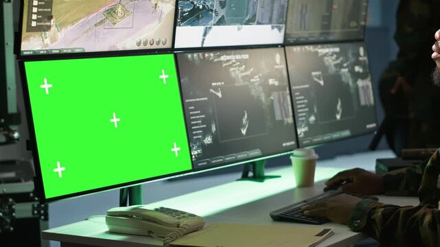 Air force officer performing tactical level surveillance in command room using mockup screen. Military specialist using radar on chroma key gear to look at assault zones, camera A