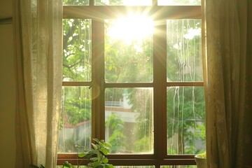 Fototapeta premium Sunlight streaming through a window with curtains, illuminating a lush green garden view.