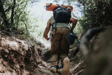 Man hiking uphill in a forest, carrying backpack and equipment, enjoying outdoor adventure on a...