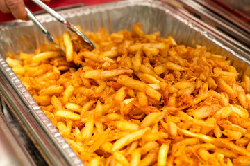 Party bowl with french fries. Tongs grabbing french fries.