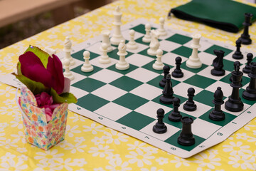 Chess board and pieces in a chess game on a picnic table.