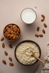 Almond milk in glass, flour in wooden brown spoon and nut kernels. Vegan or keto diet concept.