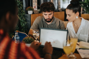 Diverse group of people collaborating in a coffee bar meeting, focusing on business strategies and ideas with laptops and drinks.