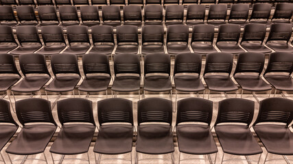 Photo of a new school theater, auditorium, large group instructional space with gray seats, chairs.	