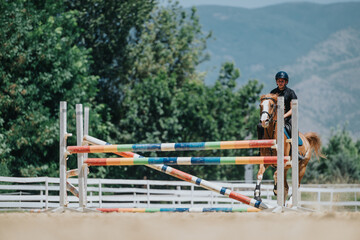 Rider and horse performing in an equestrian jumping competition, successfully clearing a colorful...