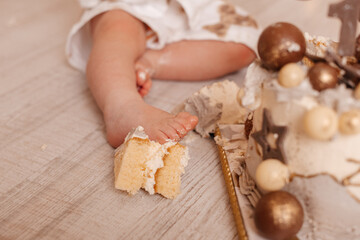 A baby’s tiny feet covered in cake crumbs, capturing a sweet and candid moment from a cake smash.