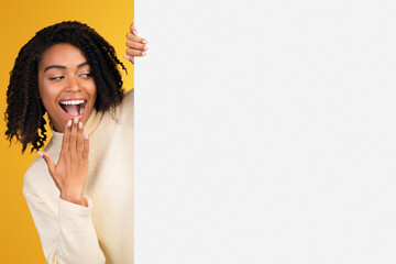 Excited Black Woman Looking Over Copy Space, Hiding Behind Blank Billboard, Peeking Out White Placard