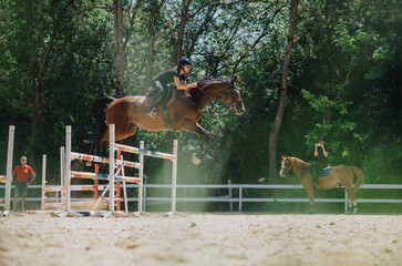 Rider and horse competing in an equestrian jumping event outdoors, showcasing the skills and grace...