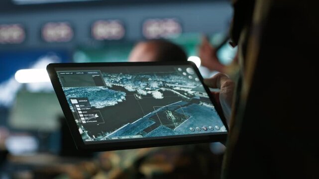 Military agent working in control room, using software on tablet, analyzing aerial reconnaissance data. Close up of intelligence corps expert controlling drones with portable device, camera A