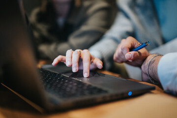 Close-up image of colleagues collaborating and discussing work on a laptop in an office setting, emphasizing teamwork and communication.