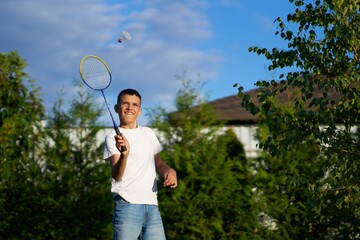 Boy playing badminton outdoors in a sunny backyard with trees