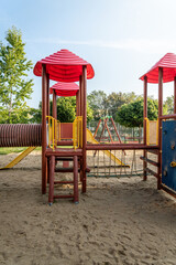 Play structure with red roofs and climbing features in a sunny playground located in a park