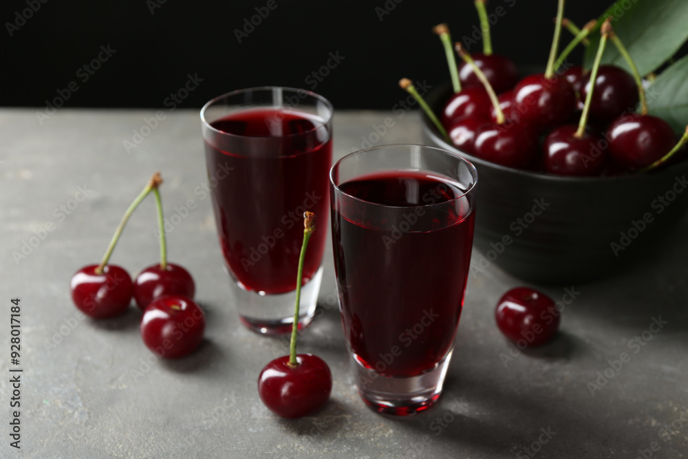 Wall mural delicious cherry liqueur in shot glasses and fresh berries on grey table