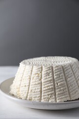 Tasty ricotta (cream cheese) on white wooden table, closeup