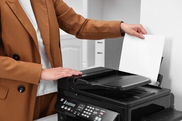 Woman using modern printer at workplace indoors, closeup