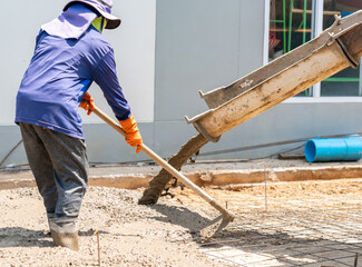 A worker shovels poured concrete from a truck.