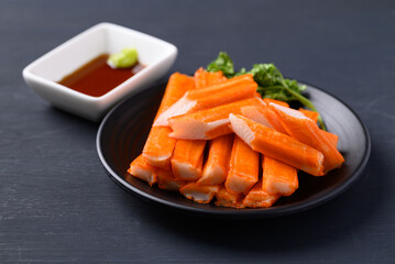 Crab sticks on black plate eating with wasabi and sauce