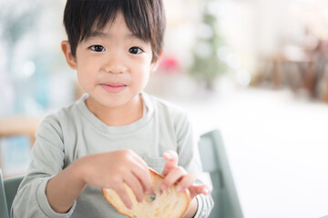 Child eating bread for breakfast, etc. Looking at the camera