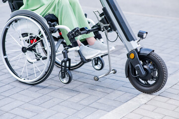 A faceless woman in a wheelchair with an assistive device for manual control. Electric handbike. 