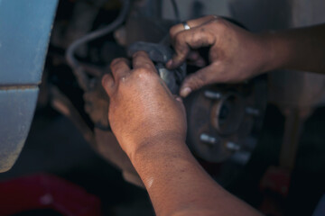 Close up Mechanic man hands repairing car auto repair shop uses jack change tyre. Man hands fixing...