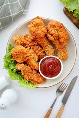 Crispy Fried chicken in a white plate with tomato sauce on white background table
